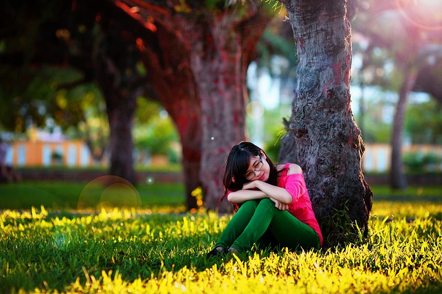 dívka sedí u stromu